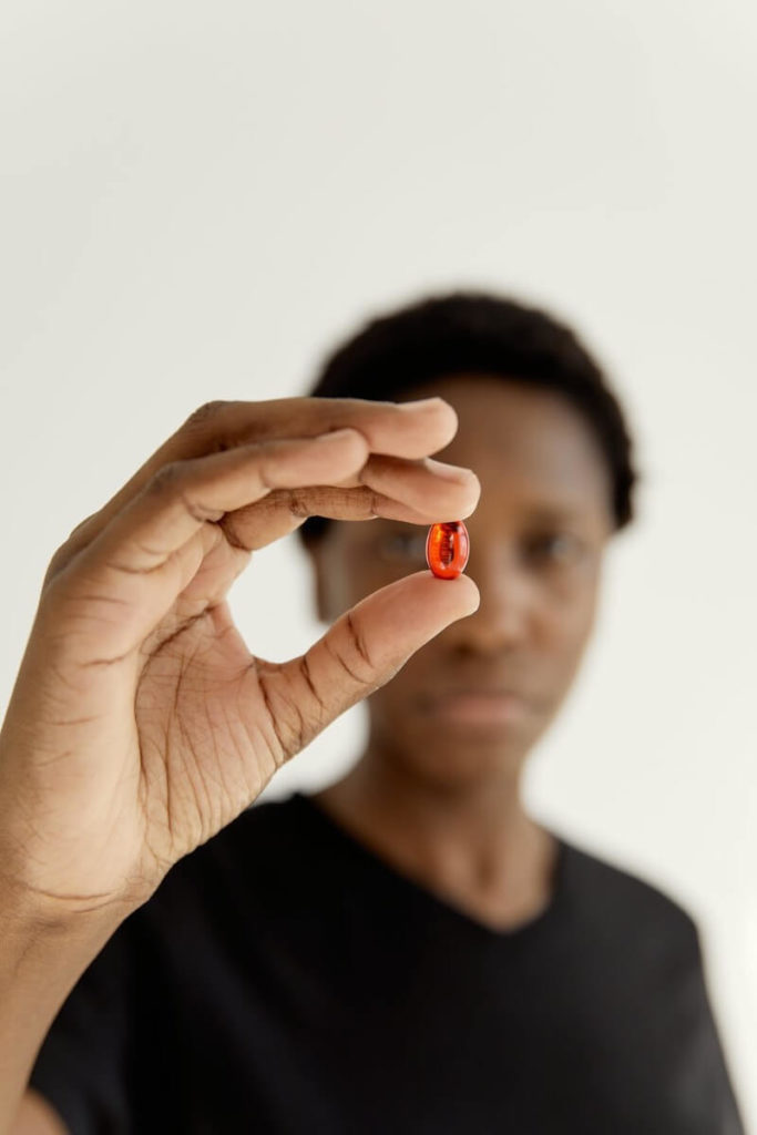 A Woman Holiding a Red Pill - Representing Taking Fat Burners Without Working Out
